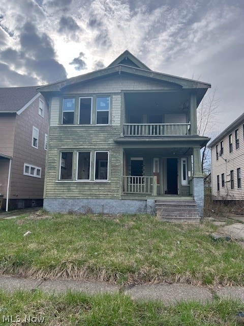 rear view of property featuring a balcony and a porch