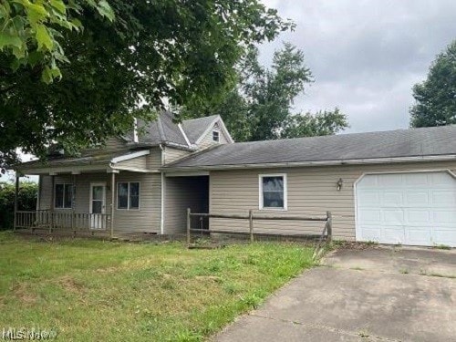 view of front facade with a garage, concrete driveway, a front lawn, and fence