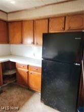 kitchen with light countertops, brown cabinetry, and freestanding refrigerator