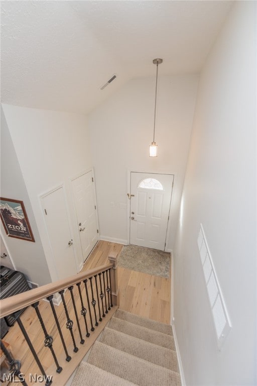 stairs with vaulted ceiling and wood-type flooring