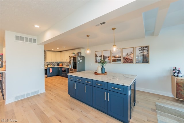 kitchen featuring stainless steel fridge, decorative light fixtures, decorative backsplash, and light hardwood / wood-style floors