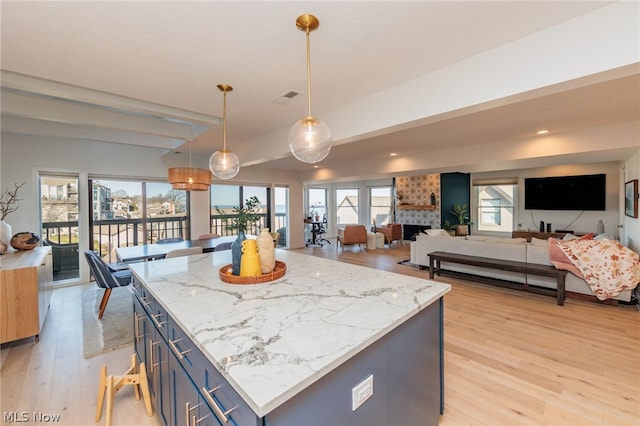 kitchen with a large fireplace, light hardwood / wood-style floors, pendant lighting, a kitchen island, and blue cabinets