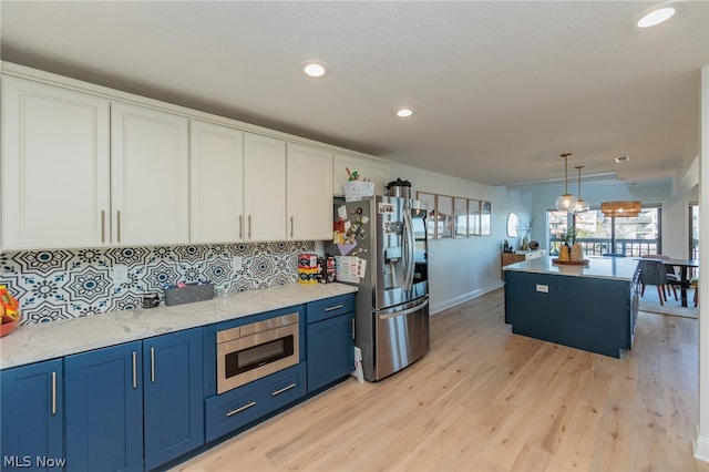 kitchen featuring light wood-type flooring, pendant lighting, blue cabinetry, stainless steel appliances, and white cabinets