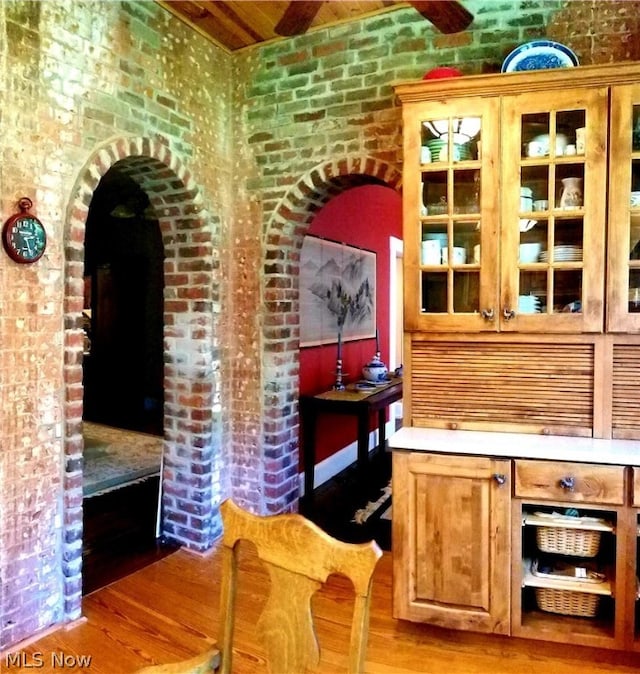 bar featuring light hardwood / wood-style flooring and brick wall