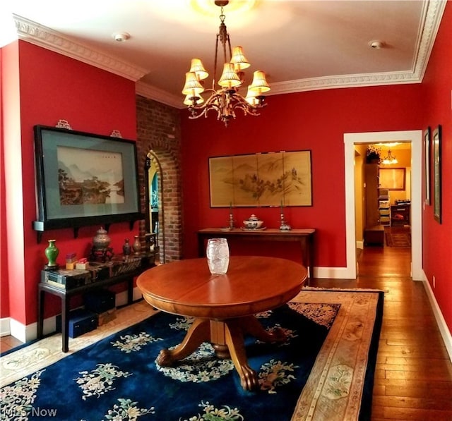 dining space featuring crown molding, a notable chandelier, brick wall, and dark hardwood / wood-style floors