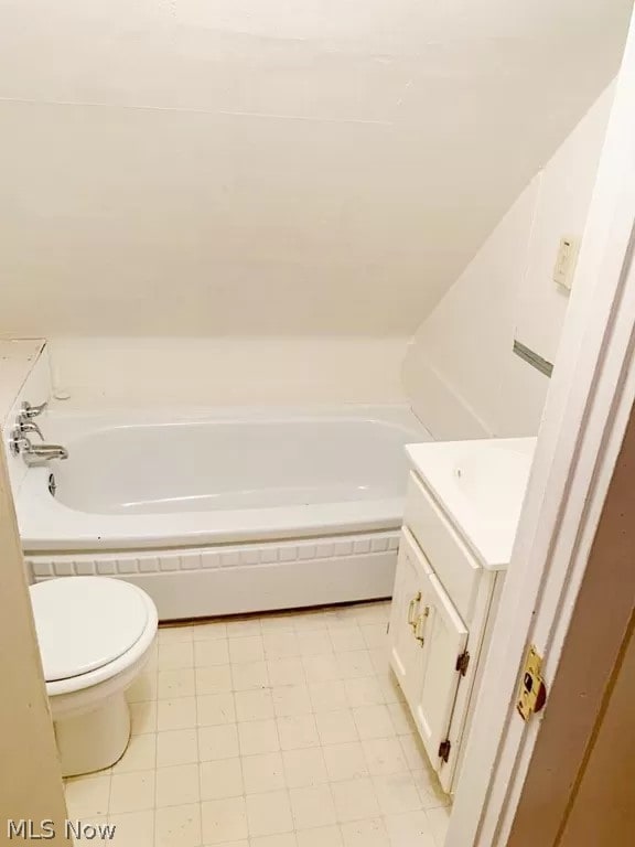 bathroom with toilet, tile flooring, vanity, and tiled bath