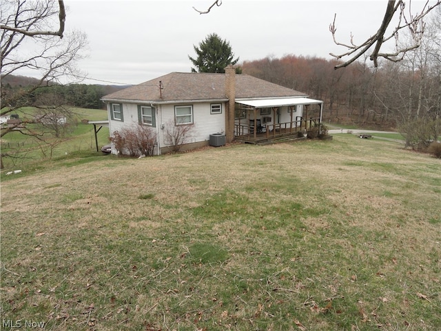 rear view of house with central AC and a lawn