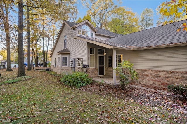 back of house with a lawn and a patio