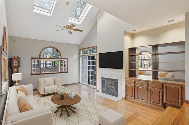 living room with high vaulted ceiling, a tile fireplace, and light hardwood / wood-style flooring