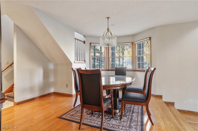 dining space featuring a textured ceiling, a notable chandelier, and light hardwood / wood-style flooring