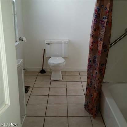 full bathroom featuring shower / bath combo, tile floors, and toilet