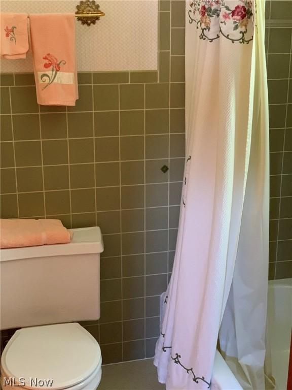 bathroom featuring toilet, tile walls, and shower / bath combo