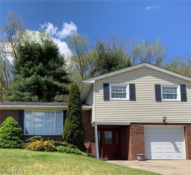 tri-level home with a front yard, concrete driveway, brick siding, and an attached garage