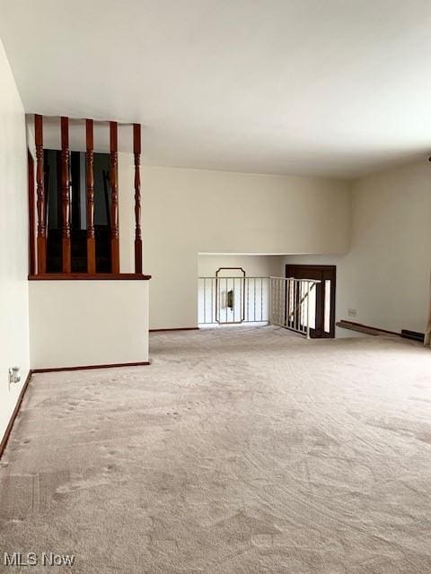 unfurnished living room featuring carpet and baseboards