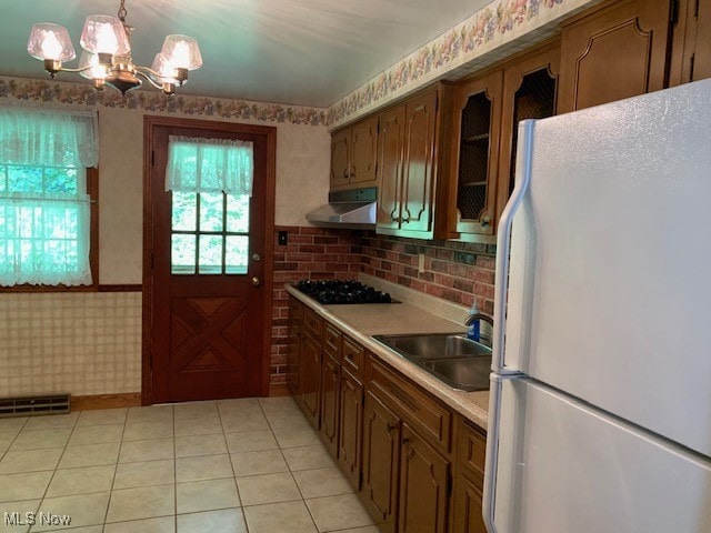 kitchen featuring hanging light fixtures, black gas cooktop, a chandelier, sink, and white refrigerator