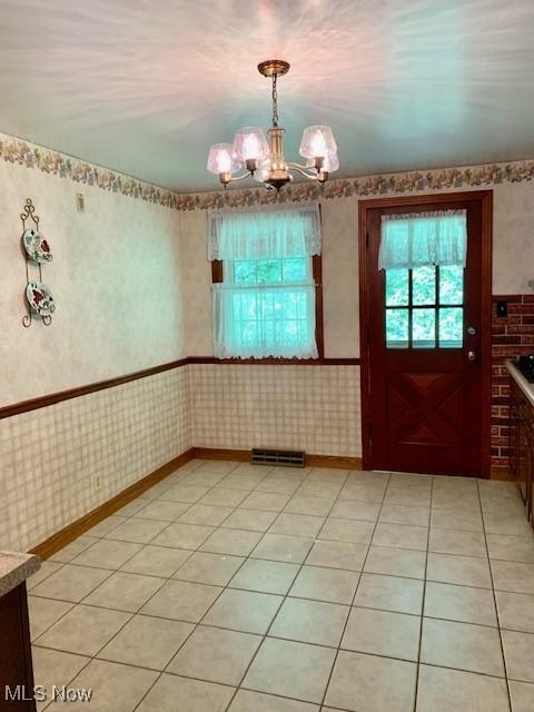 unfurnished dining area with light tile patterned floors and wallpapered walls