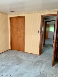 unfurnished bedroom with light carpet and a closet