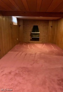 basement featuring carpet, wood ceiling, and wooden walls