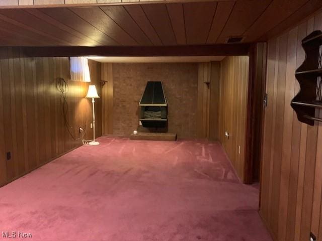 finished basement featuring wooden ceiling, carpet flooring, and wood walls