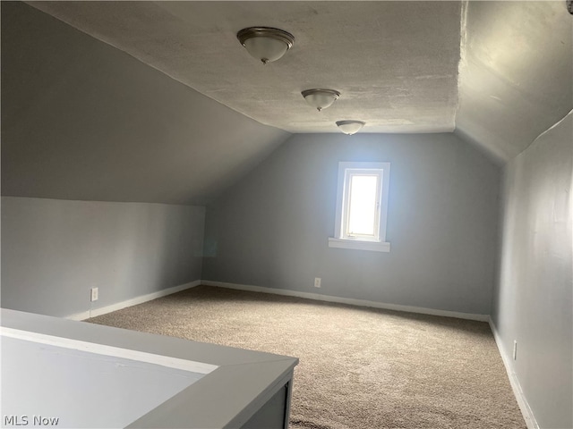 bonus room with vaulted ceiling, a textured ceiling, and carpet floors