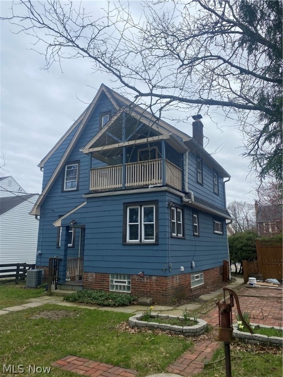 rear view of property with central AC, a balcony, and a lawn