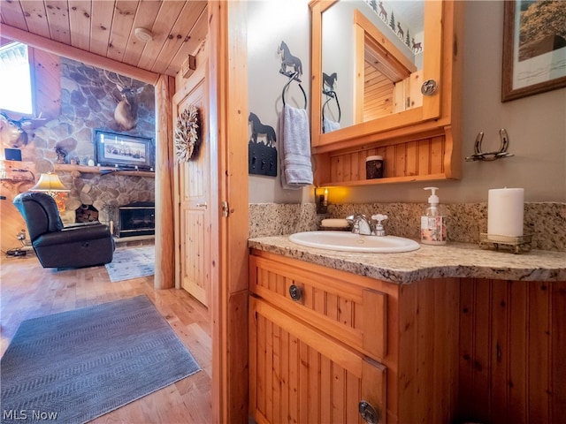 bathroom with hardwood / wood-style floors, a fireplace, large vanity, and wood ceiling