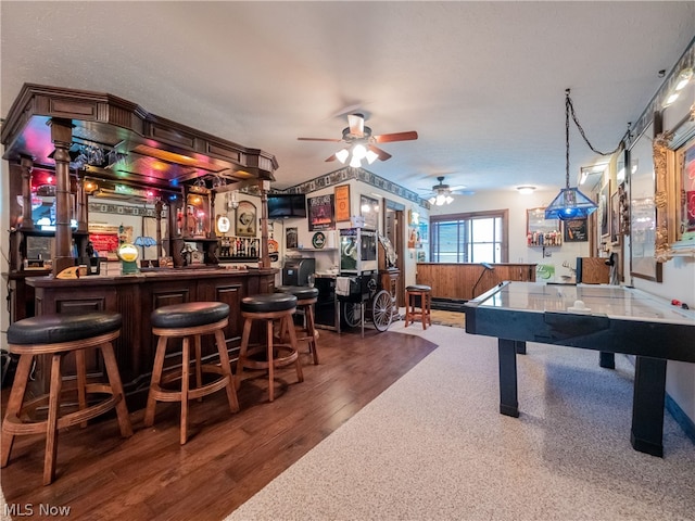 rec room with bar, ceiling fan, and hardwood / wood-style flooring