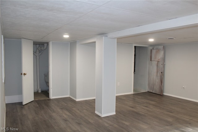 basement with a drop ceiling and dark hardwood / wood-style flooring