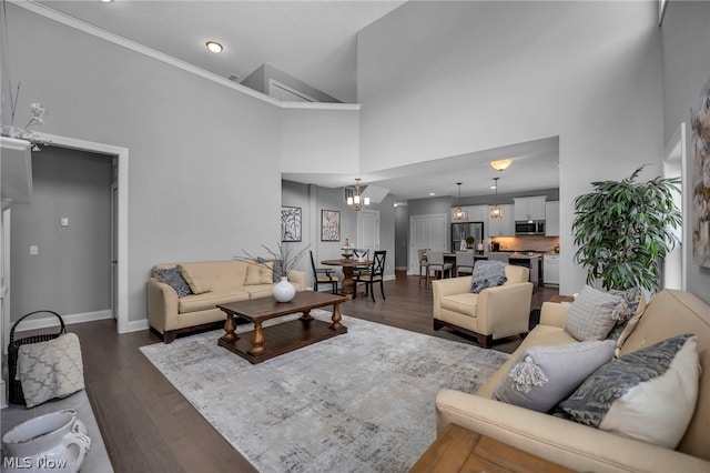 living room featuring dark hardwood / wood-style floors, crown molding, a chandelier, and a high ceiling