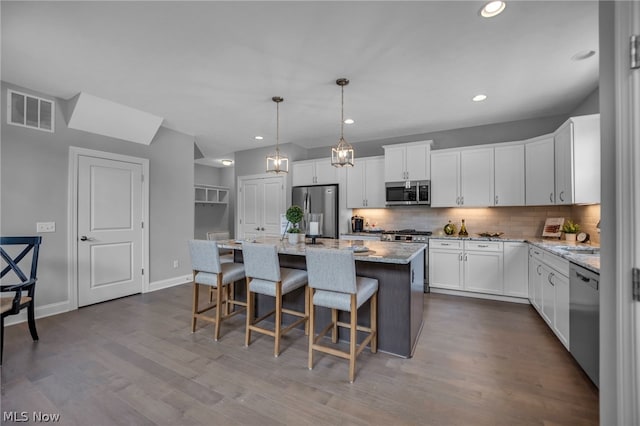 kitchen featuring a center island, pendant lighting, hardwood / wood-style floors, backsplash, and stainless steel appliances