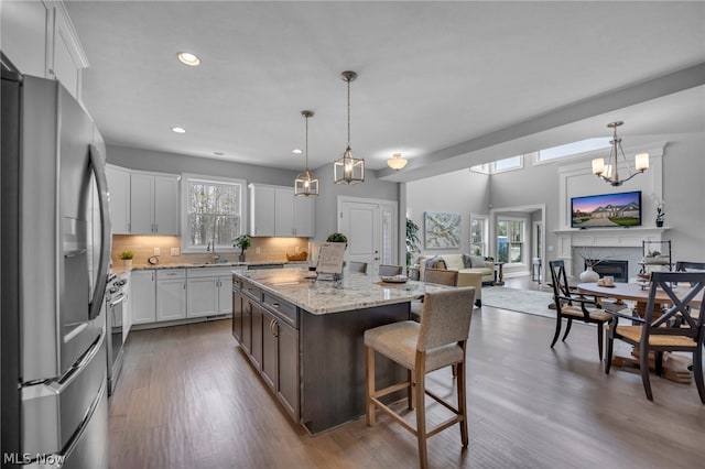 kitchen with dark hardwood / wood-style flooring, stainless steel fridge, a center island, and hanging light fixtures