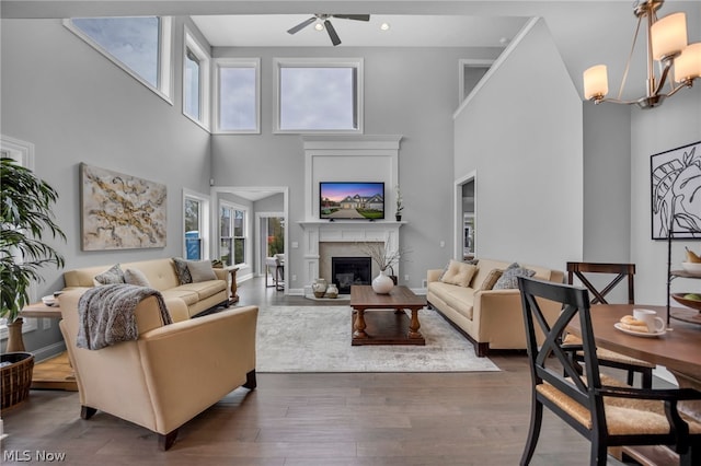 living room featuring a high ceiling, ceiling fan with notable chandelier, and hardwood / wood-style flooring