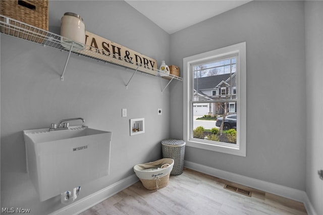 clothes washing area with washer hookup, light hardwood / wood-style flooring, and electric dryer hookup