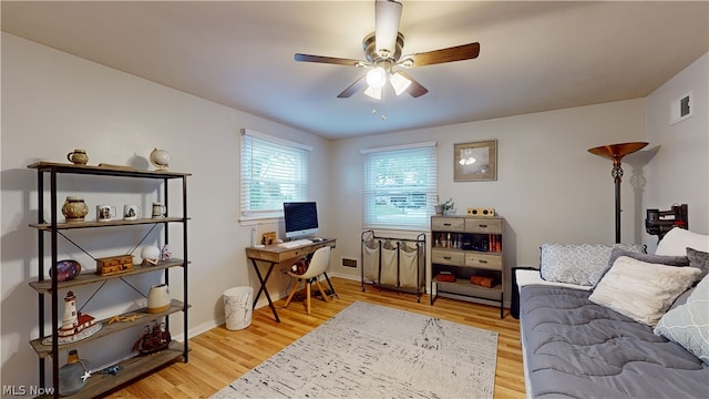 office with light wood-type flooring and ceiling fan