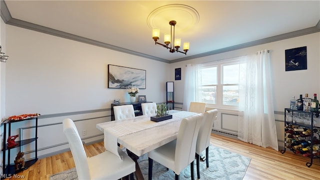 dining room featuring crown molding, an inviting chandelier, and light hardwood / wood-style flooring