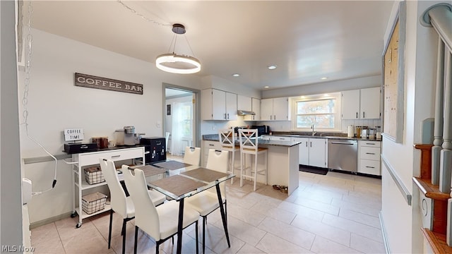 kitchen with white cabinets, sink, a center island, dishwasher, and a breakfast bar