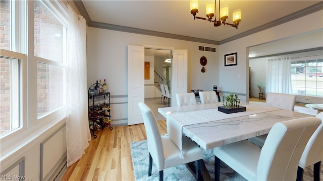 dining room with an inviting chandelier, light wood-type flooring, and ornamental molding