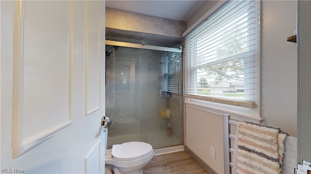 bathroom featuring a shower with door, hardwood / wood-style floors, and toilet