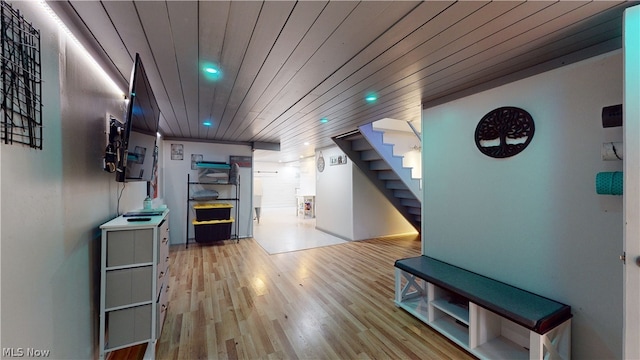 corridor with light hardwood / wood-style floors and wooden ceiling