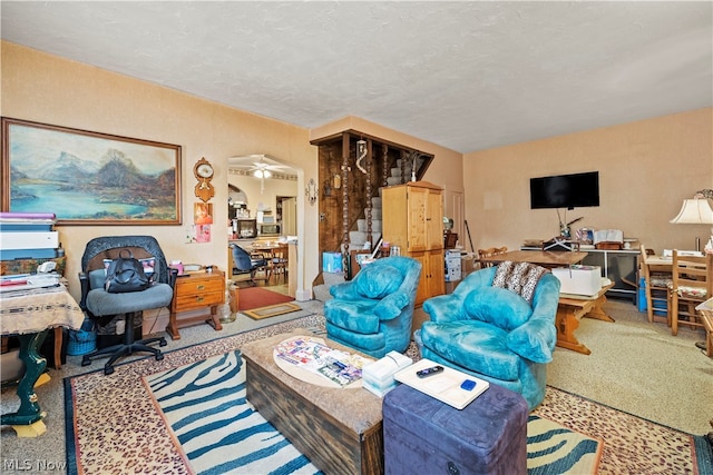 carpeted living room featuring ceiling fan and a textured ceiling