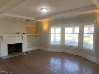 unfurnished living room featuring a healthy amount of sunlight, dark wood-type flooring, and ornamental molding