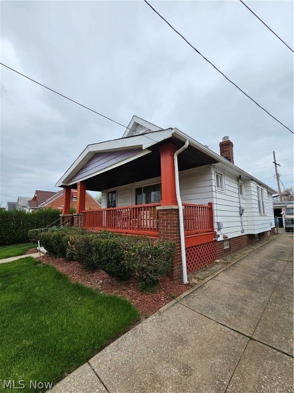 view of side of home with covered porch and a yard