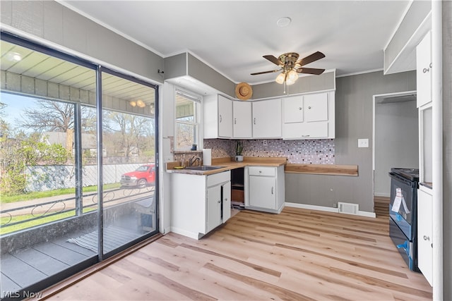 kitchen with black electric range oven, ceiling fan, white cabinets, light hardwood / wood-style floors, and tasteful backsplash