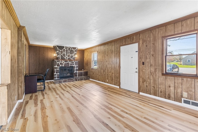 unfurnished room featuring wood walls, light wood-type flooring, a fireplace, and a textured ceiling