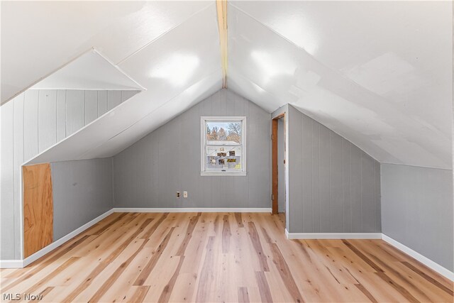 additional living space with light hardwood / wood-style flooring and vaulted ceiling