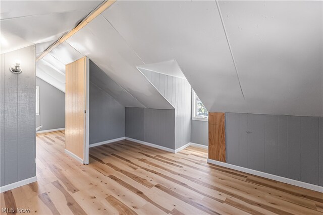 additional living space with light hardwood / wood-style flooring and vaulted ceiling