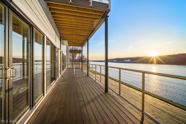 deck at dusk featuring a water view