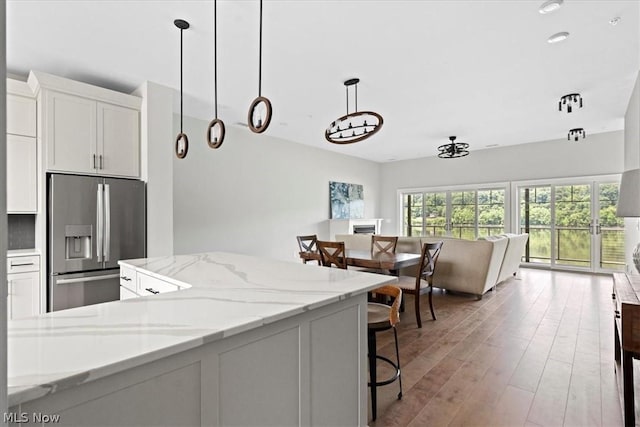 kitchen featuring white cabinets, stainless steel fridge, and decorative light fixtures