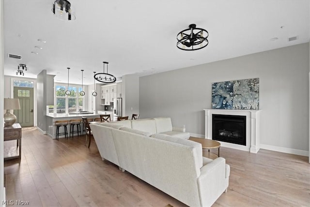 living room featuring a notable chandelier and light wood-type flooring