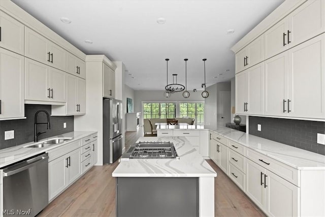 kitchen featuring pendant lighting, sink, appliances with stainless steel finishes, tasteful backsplash, and kitchen peninsula